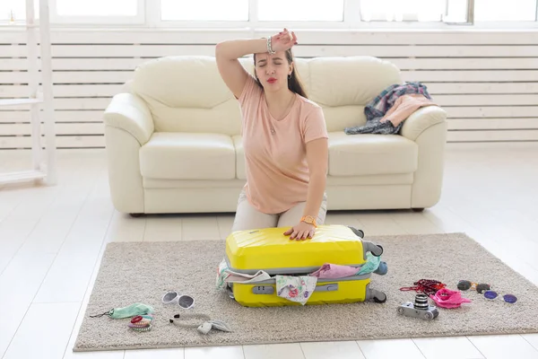 Vakantie, reis en reis concept-jonge vrouw verzamelt een koffer thuis in de slaapkamer, een heleboel dingen, vakantie en gele koffer — Stockfoto