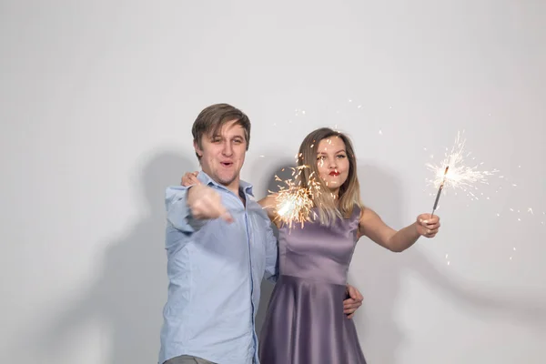 Festa, diversão e feriados conceito - jovem casal feliz com sparklers no fundo branco — Fotografia de Stock