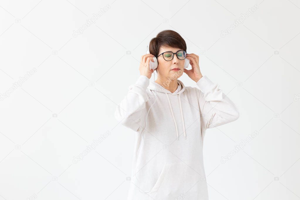 Hobby, interests and people concept - Beautiful woman 40-50 years old listening music in big headphone on white background with copy space