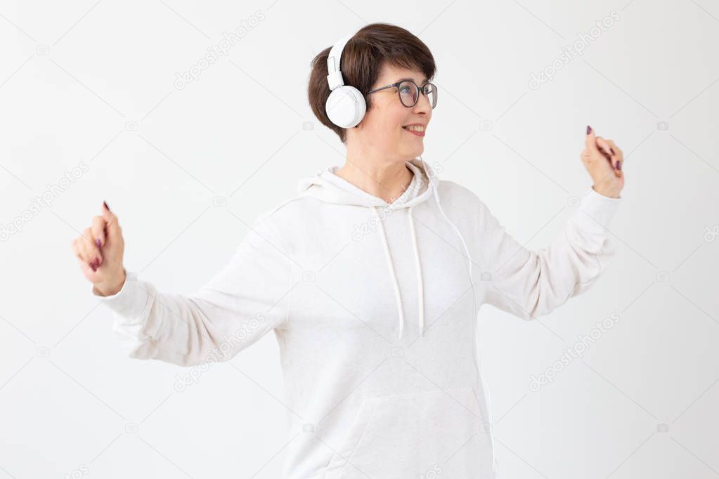 Beautiful woman 40-50 years old listening music in big headphone on white background