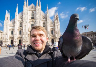 Kış seyahat, tatil ve kuşlar kavramı - selfie güvercinler yakınındaki Milan Katedrali Duomo di Milano, İtalya ile alarak genç komik adam.