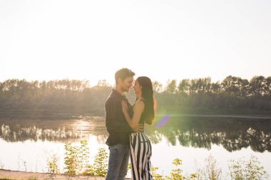 Şefkat, sevgi ve doğa kavramı - güzel kadın ve yakışıklı adam su arka plan üzerinde sarılma