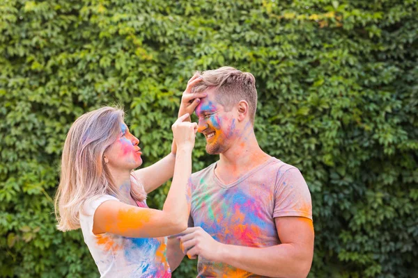 Amizade, festival de holi, conceito de pessoas - jovem casal brincando com cores no festival de holi — Fotografia de Stock