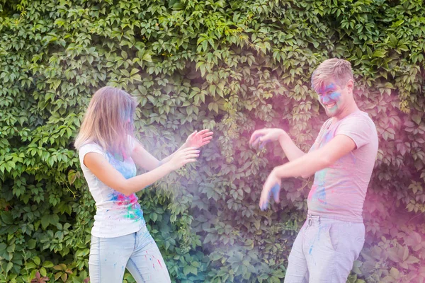 Conceito de férias, holi e pessoas - Casal feliz se divertindo coberto de tinta — Fotografia de Stock