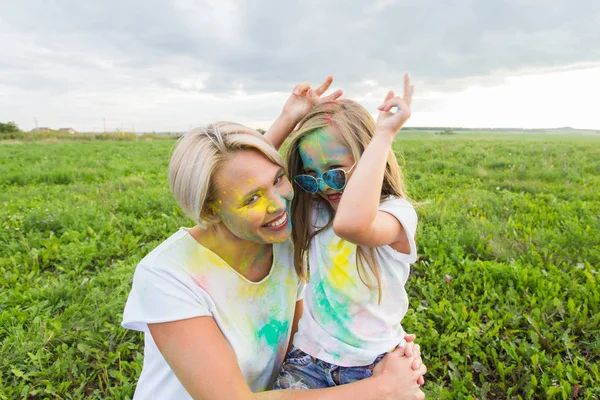 Štěstí, Holi festival a svátků koncepce - matka a její dcera pokryté barevný prášek s úsměvem nad přírodní pozadí — Stock fotografie