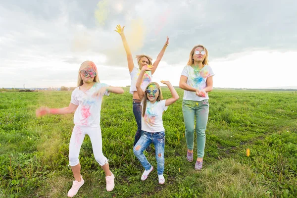Holi festival, helgdagar och lycka koncept - unga tonåringar och kvinnor i färger har kul utomhus — Stockfoto