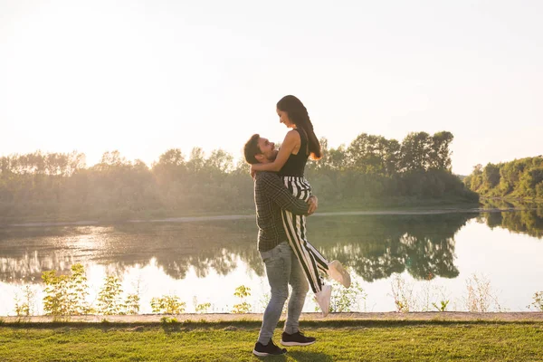 Romantik, Menschen und Sommerkonzept - Mann nahm Frau bei Sonnenuntergang am See in den Arm — Stockfoto