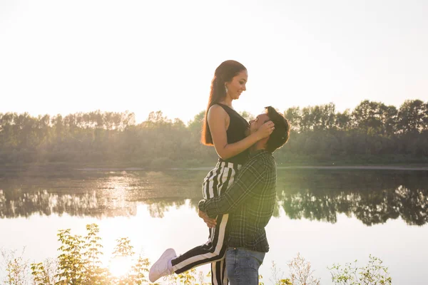 Gente, amor y concepto de la naturaleza - Hombre sosteniendo a la mujer en sus brazos sobre el fondo de la naturaleza —  Fotos de Stock