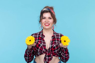 Gerberas, pin-up ve eğlenceli konsept - mavi arka plan üzerinde retro tarzı çiçekler ile neşeli genç kadın