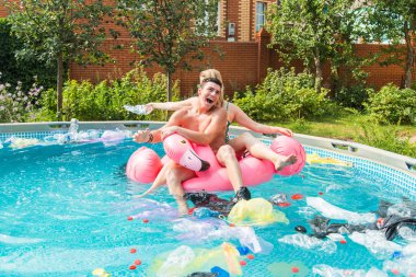 Çöp sorunu, plastik geri dönüşüm, kirlilik ve çevre kavramı - aptal adam ve kadın yüzmek ve kirli bir havuzda eğlenin. Şişeler ve plastik torbalar onlara yakın yüzer