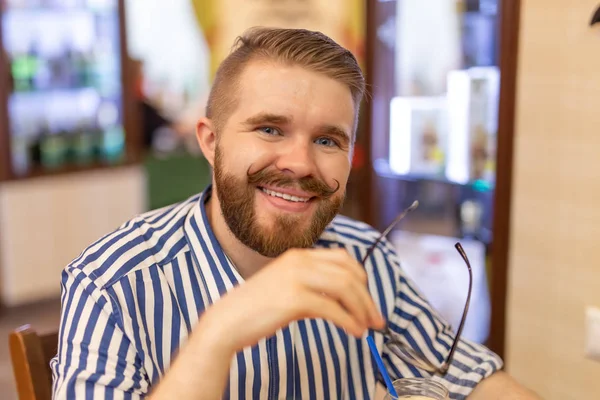 Retrato de un joven guapo con bigote y barba comiendo pizza en un café. El concepto de comida rápida poco saludable . — Foto de Stock