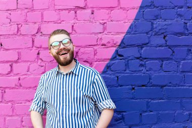 Portre bir bıyık ve kopya alanı ile mavi-mor tuğla duvara karşı poz bir sakal ile güzel bir genç öğrenci adam.