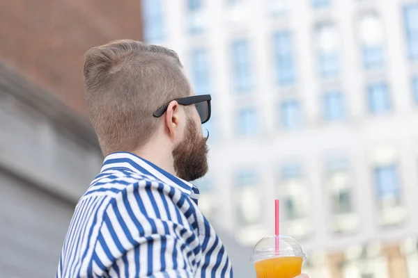 Retrato de vista inferior de un hombre hipster joven con estilo en vasos de espejo con jugo en el fondo del centro de negocios. Vacaciones urbanas en el concepto de fin de semana . — Foto de Stock