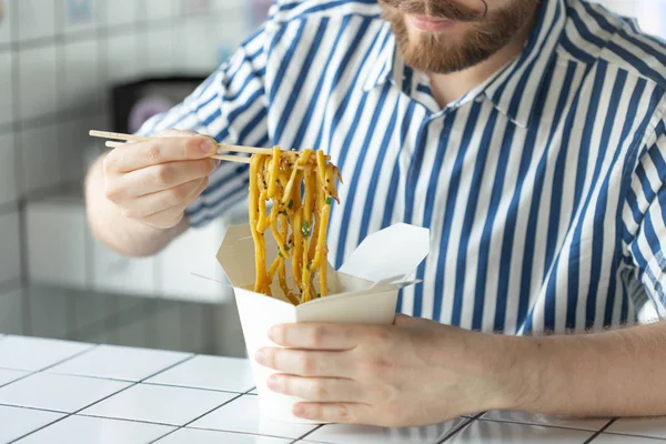 Großaufnahme eines jungen Unbekannten, der Hand in Hand mit einem Hemd Holzstäbchen in der Hand hält. köstliche asiatische Küche Konzept. — Stockfoto