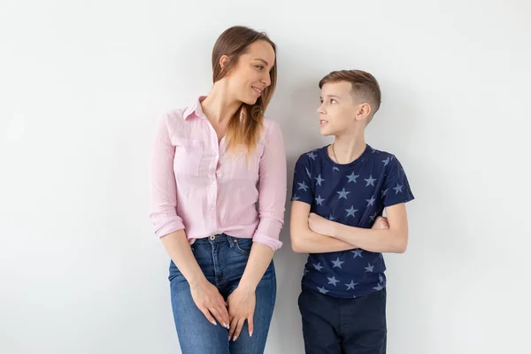 Encantadora madre joven y un lindo hijo positivo son felices mirándose mientras están de pie en la nueva sala de estar después de la mudanza. El concepto de buenas relaciones familiares y reubicación . — Foto de Stock