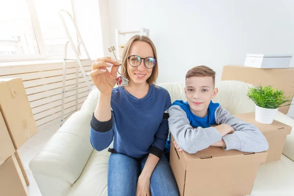 Wazig positieve moeder en zoon zitten op de Bank en het tonen van de sleutels van het nieuwe appartement. Het concept van thuis kopen op krediet-en Inwijdingsfeest. — Stockfoto