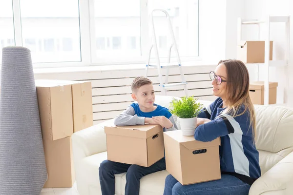 Милые мама и маленький сын сортируют коробки с вещами после переезда. Концепция ипотеки на новоселье и радость от нового жилья . — стоковое фото