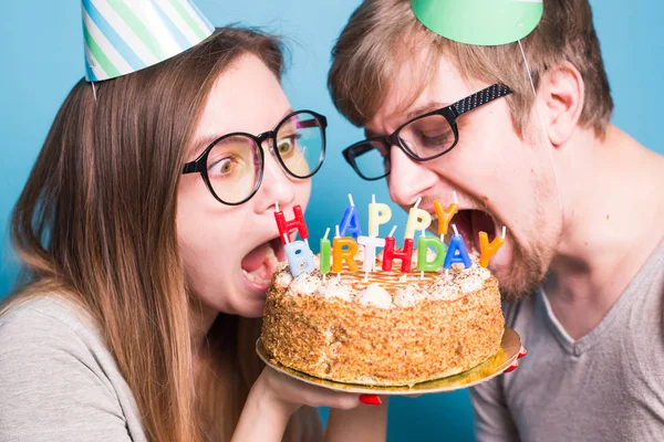 Kağıt şapkalı tuhaf genç çift kız ve erkek yakın tebrik pasta bir parça ısırmak istiyorum. Doğum günü ve tebrikler kavramı. — Stok fotoğraf
