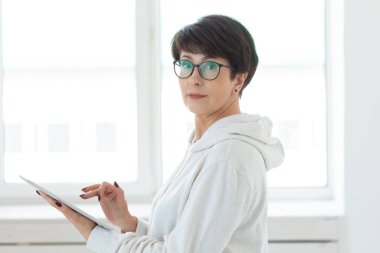 Teknolojiler ve modern insanlar kavramı-güzel kadın 50 kısa saçlı ışık odasında tablet tutarak eski yıl