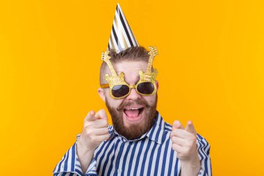 Sarı bir arka plan üzerinde bir şapka ve gözlük deli neşeli neşeli genç adam. Başarılı bir parti ve tatil kavramı.
