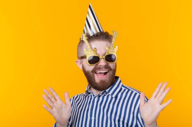 Bir kağıt kap ve gözlük neşeli genç hipster erkek mutlu sarı bir arka plan üzerinde gülüyor. Bir mega parti ve tatil kavramı.