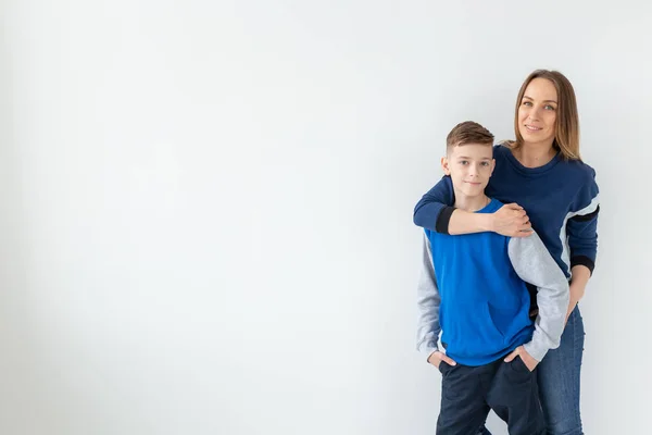 Crianza, familia y concepto de padre soltero - Una madre feliz y un hijo adolescente riendo y abrazándose en el fondo blanco con espacio para copiar — Foto de Stock