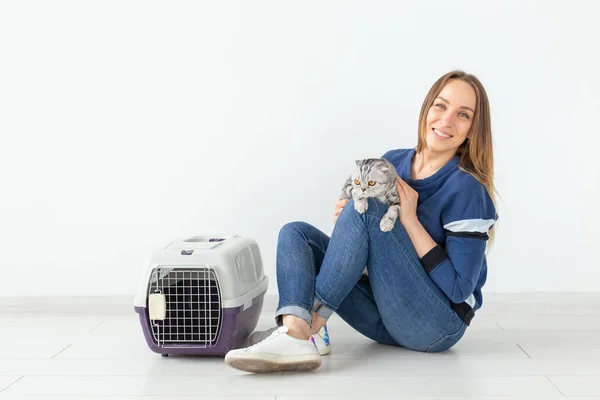 Encantadora joven positiva sostiene en sus manos a su hermoso gato escocés gris plegado sentado en el suelo en un nuevo apartamento. Concepto de mascota . — Foto de Stock