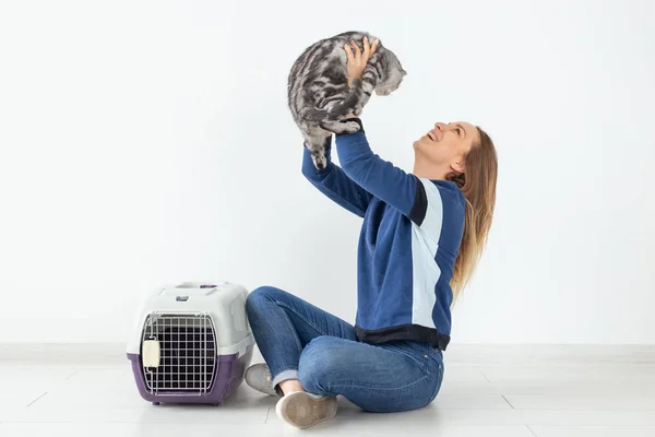 Charmante jeune femme positive tient dans ses mains son beau chat écossais pli gris assis sur le sol dans un nouvel appartement. Concept animal de compagnie . — Photo