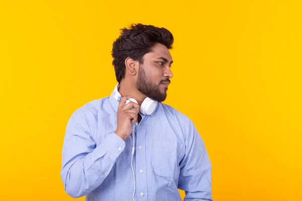 수염을 가진 잘 생긴 편안한 인도 남자는 복사 공간이있는 노란색 배경의 이어폰에서 좋아하는 음악을 듣고 있습니다. 음악 구독 개념 및 온라인 라디오. — 스톡 사진