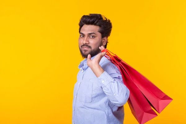 수염을 가진 인도 남자가 복사 공간이있는 노란색 배경에 포즈를 취하는 빨간 쇼핑 백을 들고있다. 슈퍼마켓 쇼핑 컨셉. — 스톡 사진