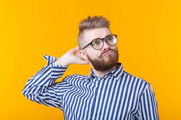 Retrato de un joven estudiante positivo con un peinado elegante con gafas y una barba posando sobre un fondo amarillo. Barbería concepto y salón de belleza para hombres . — Foto de Stock