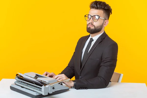 Junge, gut aussehende männliche Geschäftsleute in formeller Kleidung tippen Text auf einer Schreibmaschine posieren auf gelbem Hintergrund. Platz für Werbung. Geschäftskonzept. — Stockfoto