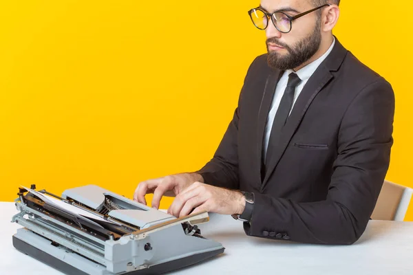 Vista lateral de un joven y encantador hombre de negocios con atuendo formal y gafas escribiendo en un texto de máquina de escribir. Concepto de negocios e ideas . — Foto de Stock