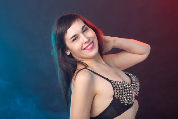 Beautiful young sexy brunette woman posing on a dark background in a riveted top on a dark background. The concept of grooming and attractiveness. — Stock Photo, Image
