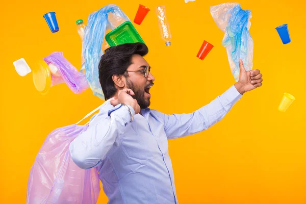 Dia Mundial do Meio Ambiente, problema de reciclagem de plástico e o homem consciente de desastres ambientais mostrando o polegar para cima enquanto carrega lixo para reciclagem em fundo amarelo . — Fotografia de Stock