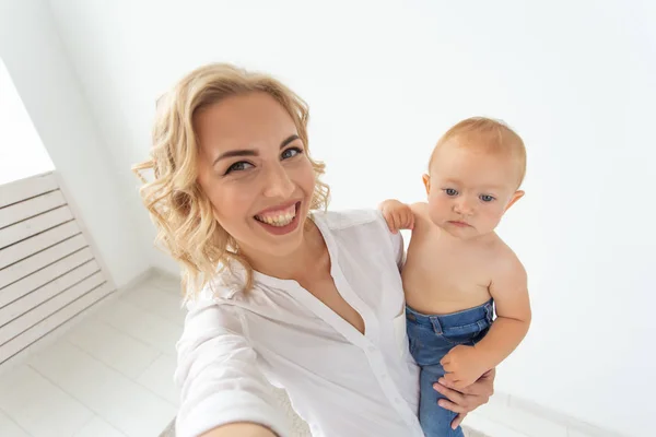 Concepto de familia y maternidad - feliz joven madre rubia con un pequeño bebé tomando selfie — Foto de Stock
