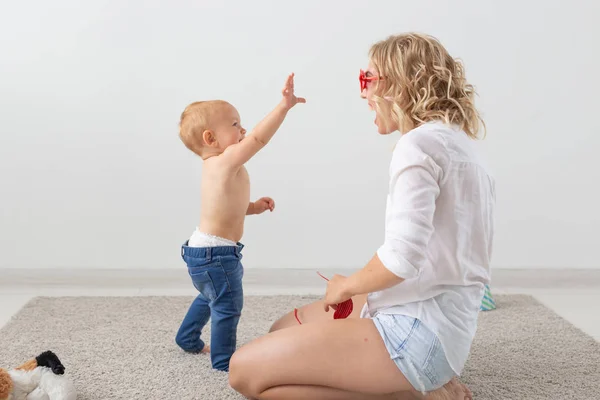 Conceito de família e parentalidade - Bebê bonito brincando com sua mãe no tapete bege — Fotografia de Stock