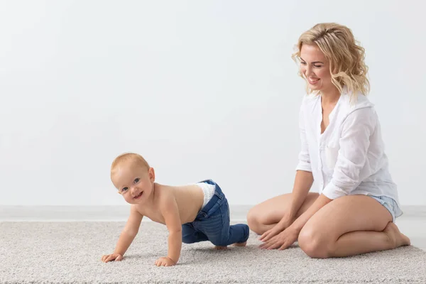 Conceito de família e parentalidade - Bebê bonito brincando com sua mãe no tapete bege — Fotografia de Stock