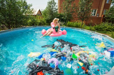 Çöp sorunu, plastik geri dönüşüm, kirlilik ve çevre kavramı - aptal kadın yüzer ve kirli bir havuzda eğlenin. Şişeler ve plastik torbalar onun yanında yüzer.