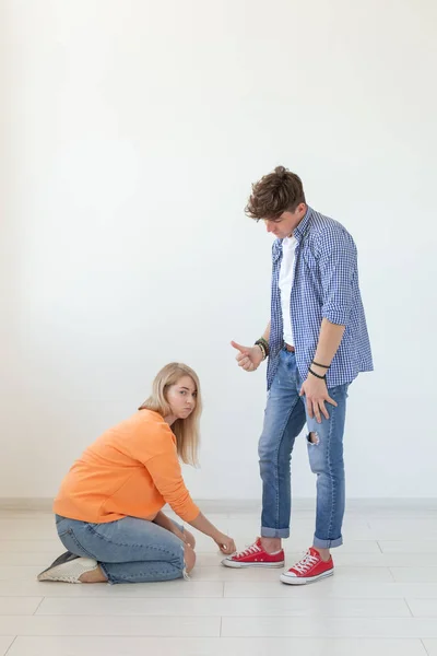 Jonge mooie blonde meid zit op haar schoot en raakt de schoenen van een vreugdevolle jongeman. Concept van ongelijke verhoudingen en seksisme. — Stockfoto