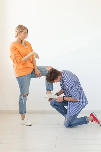 Jeune homme attachant des lacets de sa femme bien-aimée posant sur le fond blanc. Concept de courtoisie et de relations respectueuses . — Photo