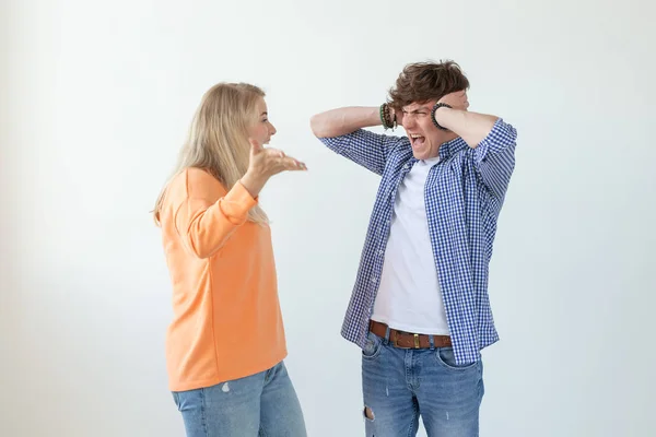 Young nervous couple wicked cute girl and upset young guy plugging ears cursing standing against white background. Misunderstanding and relationship crisis concept. — Stock Photo, Image