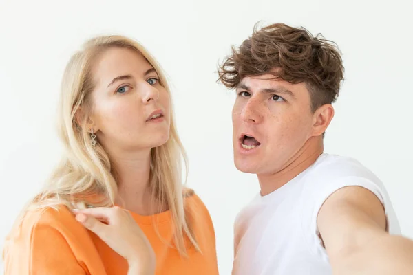 Charmante junge Paar niedliche blonde Mädchen nehmen ein Selfie posiert über weißem Hintergrund. Konzept ein junges Paar verliebter Teenager oder Millennials. — Stockfoto
