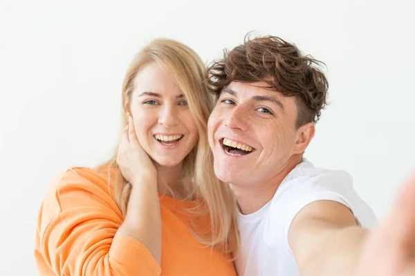 Retrato de um casal jovem alegre positivo bonito de estudantes que tomam selfie em um smartphone ou câmera. O conceito de um jovem casal apaixonado por estudantes . — Fotografia de Stock