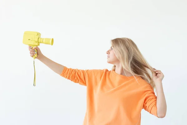 Emberek, hobbi és érdekek koncepció-gyönyörű lány tartsa sárga retro kamera fehér alapon — Stock Fotó