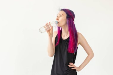 Spor salonu egzersiz sonrası renkli saç içme suyu ile Sevimli ince genç asya kadın. Su dengesini ve sağlıklı bir yaşam tarzını yenileme kavramı. Kopyalama alanı ile beyaz arka plan