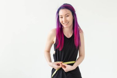 Mor saçlı kimliği belirsiz genç kız hipster copyspace ile beyaz bir arka plan üzerinde bir ölçüm bandı ile bel ölçer. Sağlıklı yaşam tarzı kavramı.