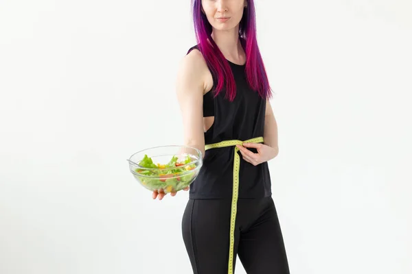 Mladá neidentifikovaná ženská sportovec s purpurovými vlasy měří pas měřicí pásky a drží zeleninový salát. Koncepce správné výživy a dobrého tvaru. — Stock fotografie