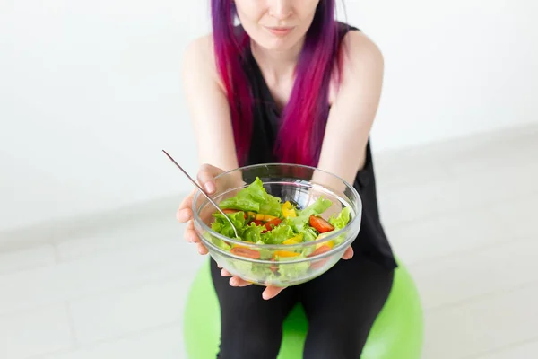 Close-up of asian fitness girl with colored hair holding in hands vegetable salad. Healthy eating concept.