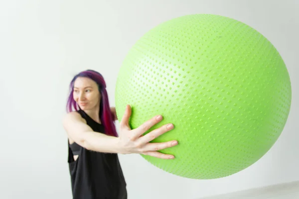 Niña alegre positiva borrosa hipster sosteniendo una pelota verde en sus brazos durante las clases en el gimnasio. Concepto de yoga y pilates y fitness . — Foto de Stock